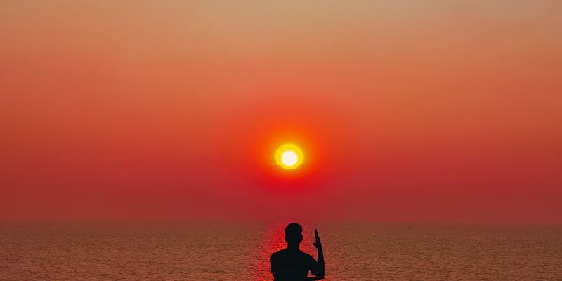 Silhouetted figure moving smoothly during a sunset yoga practice.